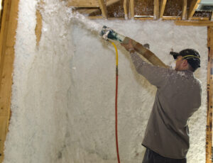 Worker blowing insulation into the wall of a newly framed house